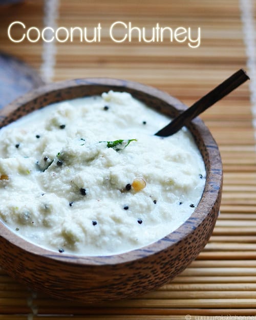 coconut chutney - a wooden bowl of fresh coconut chutney with a spoon.