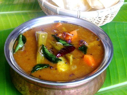 sambar - a lentil and vegetable stew in a steel bowl on a banana leaf.