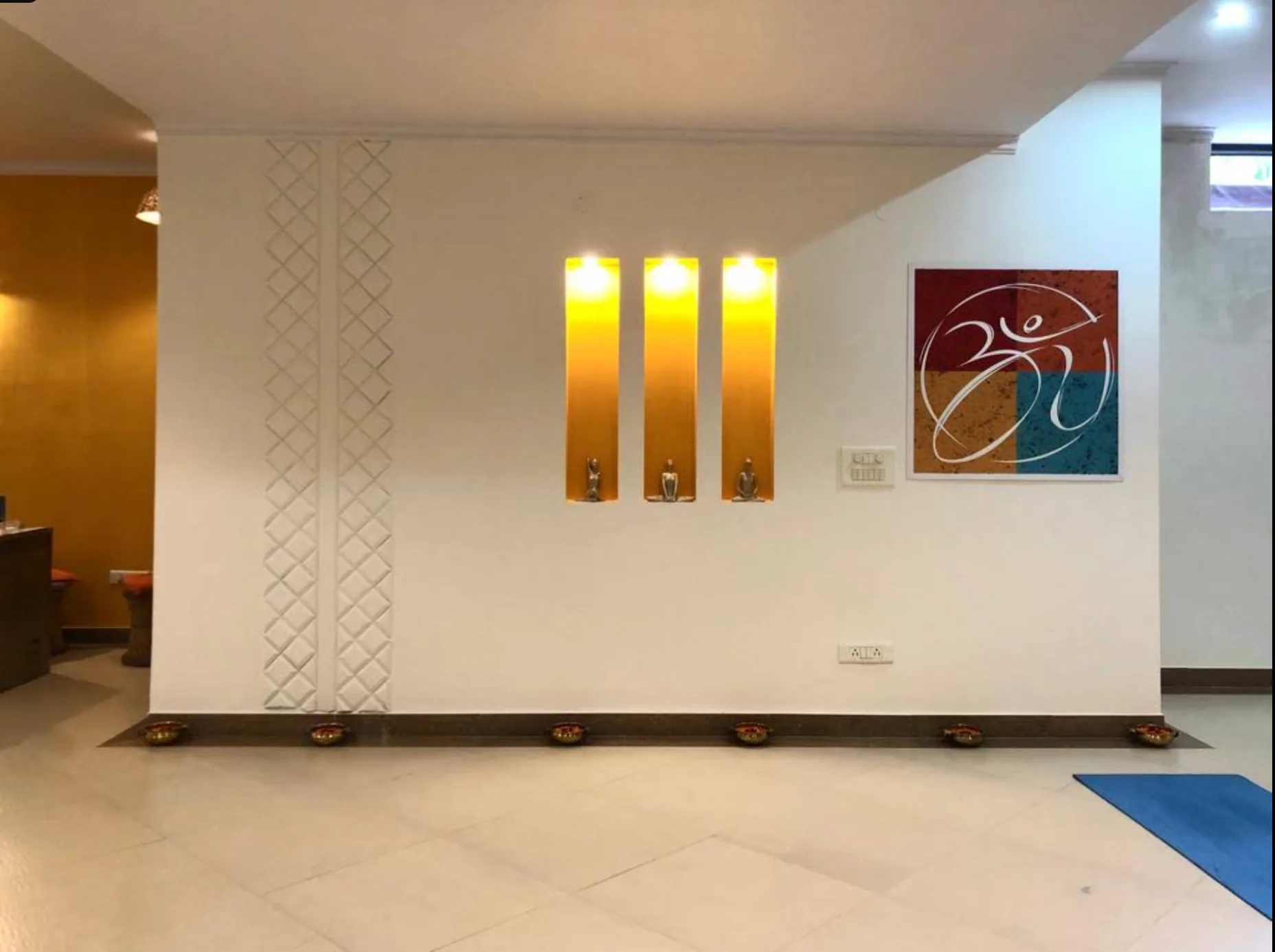 Sivananda Gurgaon centre image with three lit diyas, a framed Om painting