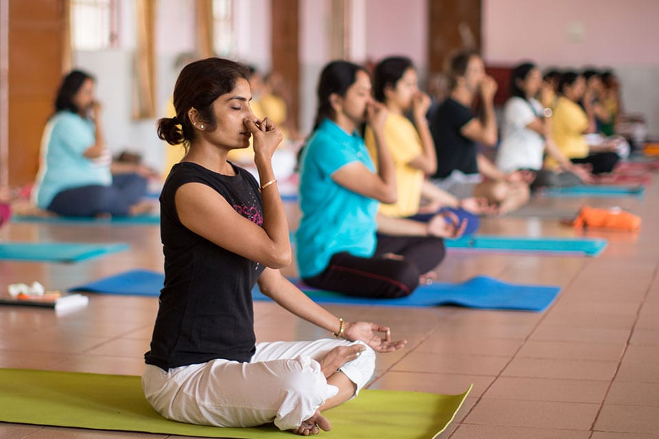 pranayama at yoga retreat - a class practicing alternate nostril breathing.
